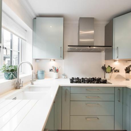 Üldine sisevaade kodus olevast modernsest metallrohelisest köögist koos valge kvartsist töötasapinnaga ja valamu all