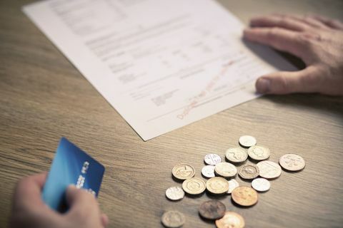Manssi käes hoiab müntidega krediitkaart ja arve laual