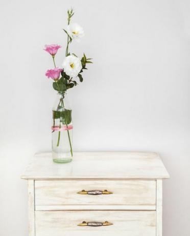 Taaskasutusse võetud lisianthuse lillekimbuga valge seina vastas lillekimp