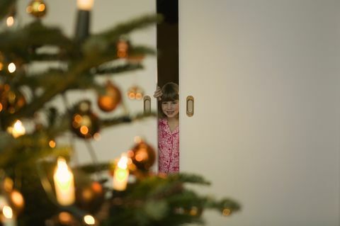 Tüdruk pidžaamas peering läbi jõulupuu ukse